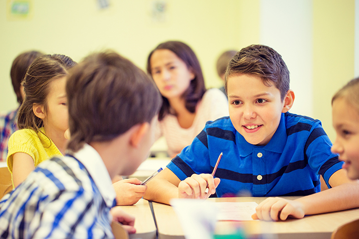 education, elementary school, learning and people concept - group of school kids talking during lesson in classroom